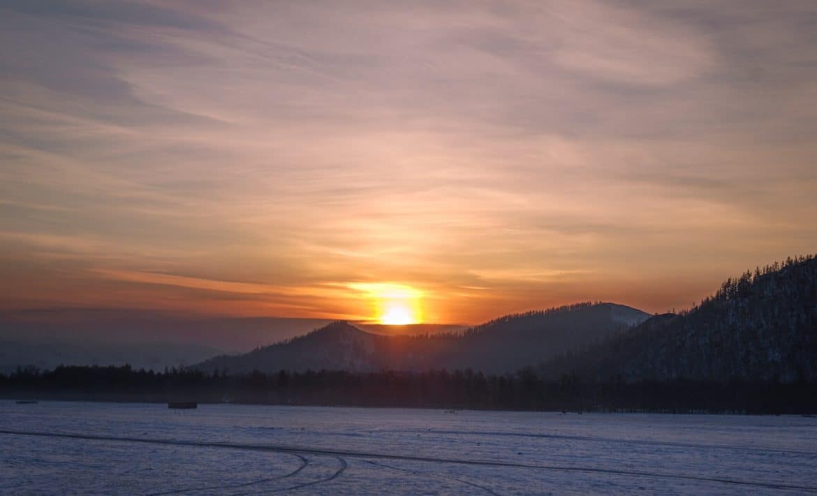 body of water near mountain during sunset